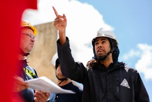 Ingenieur mit Helm zeigt mit Finger auf Baustelle
